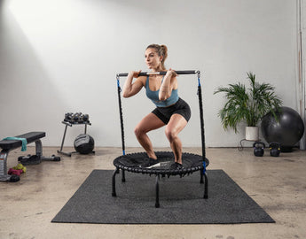 Woman squatting on a JumpSport trampoline during a strength training workout.